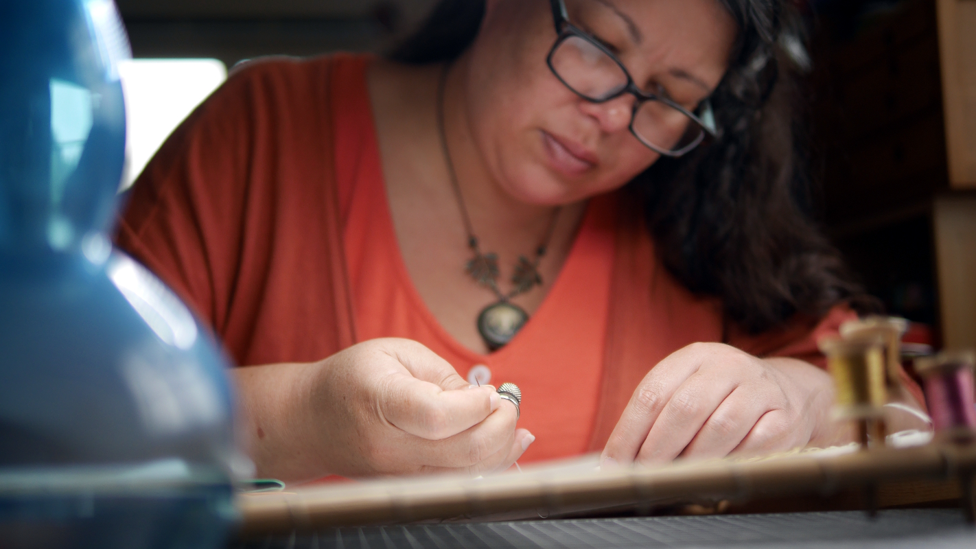 potrait d'une femme brune penchée sur sa broderie