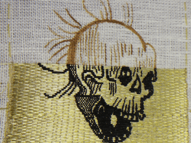 GIF animé de la broderie d'un crane sur fil d'or. On voit la broderie qui avance ligne de fil d'or par ligne de fil d'or avec le dessin en noir par dessus.