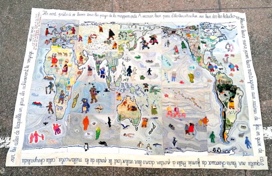 Planisphère brodé d'après la carte Peters qui donne des proportions plus allongées à l'hémisphère sud par rapport à nos habitudes. Elle est colorée et de nombreux personnages sont brodés partout. Autour un poème est brodé.