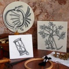 Photo de 3 broderies en noir sur blanc dans le style des gravures de la renaissance. Elles représentent un sablier penché en déséquilibre sur un caillou, un dragon qui se mord la queue en formant un cercle et un arbre fruitier avec le tronc et les branches entrelacés. Une faux négligemment posée contre le tronc.