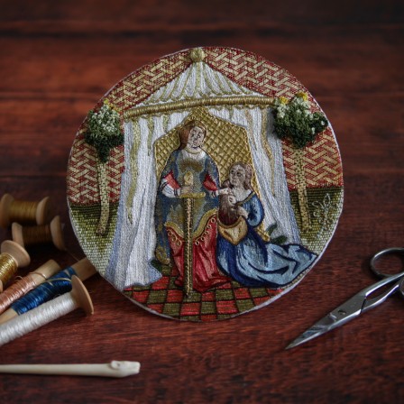 Médaillon brodé dans le style médiéval au fil d’or et se soie multicolore. La broderie représente une scène de l’Ancien testament : Judith et sa servante, devant une tente, qui placent la tête d’Holopherne dans un sac.