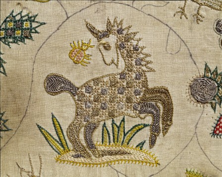 Détail d'une broderie avec des décors végétaux et une licorne. La broderie est réalisées avec des fils colorés et des détails dans la licorne sont brodés au fil d'or