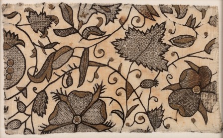 Broderie sur toile écrue au fil noir et au fil doré. C'est un décors végétal avec des points linéaires pour les contours et les tiges et des motifs géométriques au fil noir pour le remplissage. Des détails sont brodés au fil d'or avec des points tressés