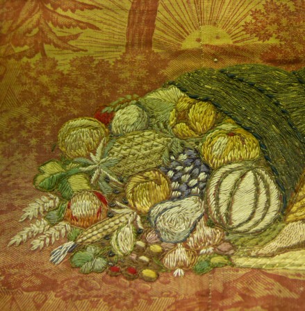 Détail des fruits variés qui sortent de la corne d'abondance : melon, ananas, poire, maïs, raisin, blé, ail...